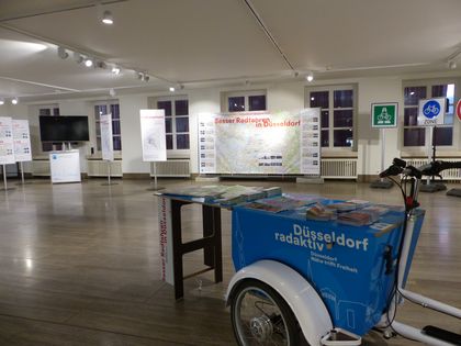 Bild von Ausstellung mit einzelnen Exponaten wie einem LAstenrad und einzelnen Infostelen