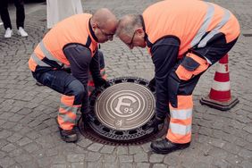 Zwei Mitarbeiter des Stadtentwässerungsbetriebs der Landeshauptstadt Düsseldorf beim Einsetzen des F95-Kanaldeckels. Foto: F95