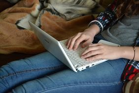 Jugendliche tippt auf Laptop-Tastatur