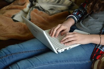 jugendliche Person tippt auf Laptop-Tastatur