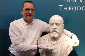 Conchyliensammler Roland Günther umarmt die Marmorbüste des Museumsgründers Theodor Löbbecke und hält die neu beschriebene Meeresschnecke in seiner Hand