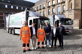 Gruppe vor den beiden neuen elektrischen Müllsammelfahrzeugen am Rathaus