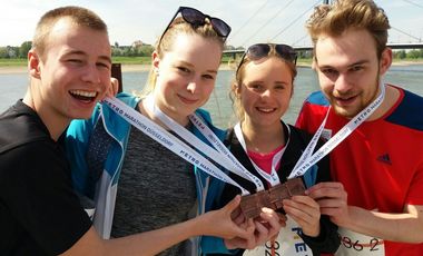 Vier Jugendliche mit ihren Medaillen am Rheinufer