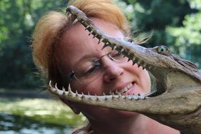 Frau mit Krokodilpräparat, dessen Maul weit geöffnet ist