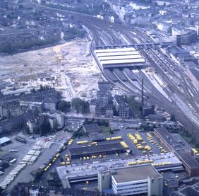 1983: Luftaufnahme vom Hauptbahnhof während des großen Umbaus. Während an den ersten Gleisen die Überdachung noch fehlt, ist sie an den hinteren Gleisen schon sichtbar. Im Vordergrund das Gelände der Post