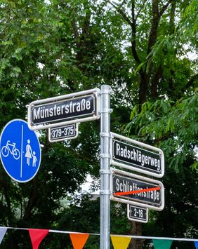 Unterhalb des neuen Straßennamens bleibt das bisherige Straßenschild für ein Jahr durchgestrichen hängen. Ein QR-Code am Mast verweist auf den Hintergrund zur Umbenennung. Foto: Uwe Schaffmeister