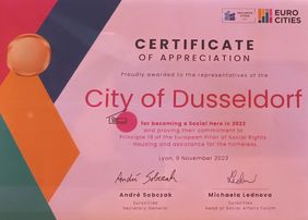 Die Landeshauptstadt Düsseldorf wurde beim EUROCITIES Social Affairs Forum in Lyon als "Social Hero" für ihr Engagement bei der Versorgung Obdachloser ausgezeichnet. Auf dem Bild ist hierzu ein Zertifikat zu abgebildet. © Landeshauptstadt Düsseldorf
