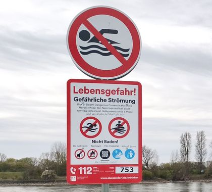 Schild, das auf die Gefahren des Schwimmens im Rhein hinweist