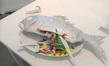 Kunstobjekt Fisch mit Plastikmüll auf einem Teller