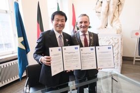 Kensaku Morita, Gouverneur der Präfektur Chiba, und Oberbürgermeister Thomas Geisel präsentieren den unterzeichneten Partnerschaftsvertrag. Foto: Michael Gstettenbauer