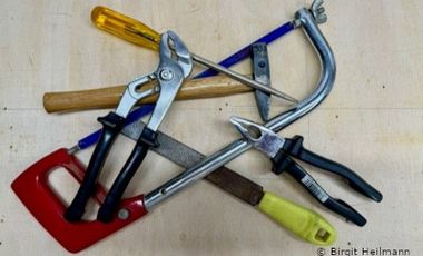 Foto mit unterschiedlichen Werkzeugen: Säge, Zange, Feile, Schraubenzieher und Hammer.