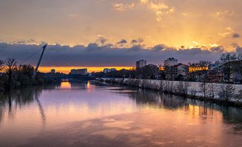Die Garonne in Toulouse bei Sonnenuntergang mit einer Fußgängerbrücke, die von der Stadt auf die Île du Ramier führt.
