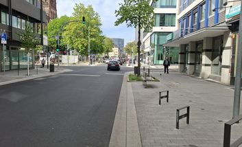 Foto von neuem Abschnitt der Friedrichstraße. Im Seitenraum sind Fahrradabstellbügel zu sehen und der breite, hell gepflasterte Gehweg.