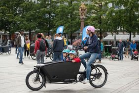 Foto von einem Mutter, die Ihr Kind in einem Lastenrad transportiert.