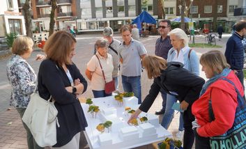 Das Foto zeigt ein Gruppe von Bürgerinnen und Bürgern auf dem Breidenplatz, die ein Modell des Platzes betrachten und darüber diskutieren.