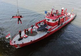 Der Höhenretter der Feuerwehr seilt sich mit dem Verletzten auf das Löschboot ab. Foto: Landeshauptstadt Düsseldorf/David Young