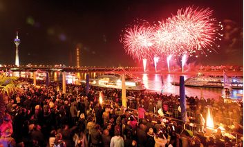 Zuschauer betrachten ein Feuerwerk an der Rheinuferpromenade