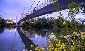 Eine Fußgängerbrücke bei Sonnenuntergang, die in Toulouse über die Garonne auf die Île du Ramier führt.