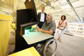 Helge Hahn, Mitglied des Behindertenrates, demonstrierte Oberbürgermeister Dr. Stephan Keller (hinten) und Sabine Humpert-Kalb, Vorsitzende des Behindertenrates, die Ausleihe an einem elektrisch höhenverstellbaren Gerät. Foto: David Young