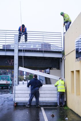 Die Arbeiter bei der Installation der Schutzwand am Durchgang vom Unteren Rheinwerft zum Alten Hafen in der Düsseldorfer Altstadt. Foto: Michael Gstettenbauer