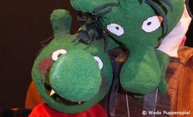 Foto von zwei grünen Puppentheaterpuppen mit dicken Nasen - die Olchis.