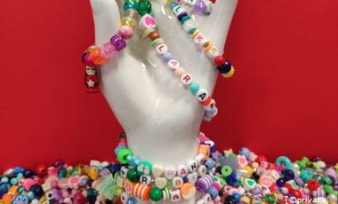 Foto von einer weißen künstlichen Hand mit Perlenarmbändern und losen Perlen