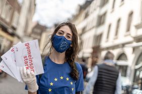 Die Mund-Nasen-Bedeckung aus Stoff soll im Europa-Monat Mai die europäische Solidarität symbolisieren. Er ist mit den Europa-Sternen und dem Schriftzug Düsseldorf versehen; Foto: Lars Heidrich