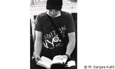 Schwarzweiß Foto eines Mannes, der in einem Buch liest.
