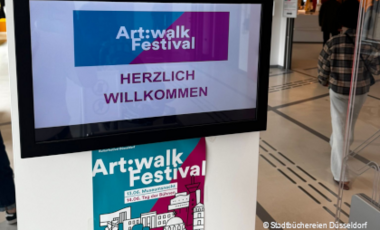 Monitor und Plakat zum Art:walk Festival 2026 im Eingang der Zentralbibliothek