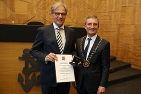 Kulturdezernent Hans-Georg Lohe mit Urkunde und Ehrenring neben OB Geisel im Plenarsaal