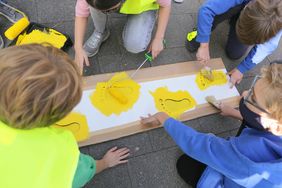 Viertklässler im Einsatz: Mit Schablonen wurden gelbe Fußabdrücke auf den Schulweg gemalt. Foto: Ingo Lammert