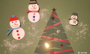 Gebastelte Winterdekoration: Drei kleine Schneemänner und ein Tannenbaum.