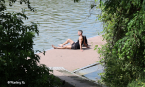 Foto von einem Mann, der am Ufer eines Flusses sitzt