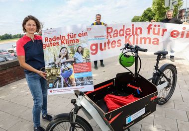Foto mit 3 Mitarbeitern des Umweltamtes die ein Poster und einen Banner zum Stadtradeln in der Hand halten und um ein Lastenrad stehen.