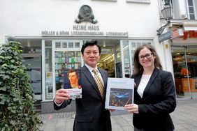 Der chinesische Generalkonsul Feng Haiyang und die Leiterin des Büros für Internationale, Regionale und Europäische Angelegenheiten, Jessica Dedic vor dem Heinrich-Heine-Haus, mit jeweils einem Buch aus der Spende