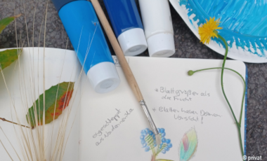 Foto von einem Notizbuch mit Pinsel, Farben und Pflanzen