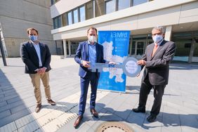 Oberbürgermeister Dr. Stephan Keller (M.), Schulleiter Guido Gehre (r.) und Michael Köhler von der IPM bei der symbolischen Schlüsselübergabe vor dem Neubau. Foto: Gstettenbauer
