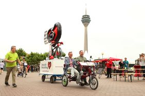 Unter dem Motto "Fahr dem Herzinfarkt davon" wirbt die Deutsche Herzstiftung für das Fahrradfahren. Oberbürgermeister Thomas Geisel und der Künstler Jaques Tilly präsentieren eine Großplastik, die Tilly eigens dafür geschaffen hat.