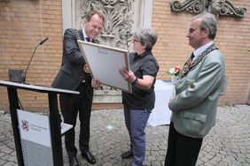 Schaustellerehrung im Rathausinnenhof 2023: Oberbürgermeister Dr. Stephan Keller mit Schaustellerin Angela Bruch und Schützenchef Michael Zieren (v.l.) bei der Überreichung der Urkunde, Fotos: Gstettenbauer.
