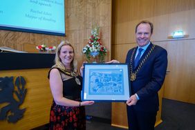 Councillor Rachel Eden übergibt Oberbürgermeister Dr. Stephan Keller ein Bild mit Motiven des Reading Museums und des Riverside Museums Reading als Gastgeschenk.