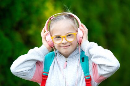 Fröhliches Kind mit Downsyndrom, das Kopfhörer trägt, Foto: iStock, Eleonora_os
