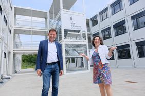 Stadtdirektor Burkhard Hintzsche und Dr. Antonietta P. Zeoli, Schulleiterin des Wim-Wenders-Gymnasiums, vor den Schulcontainern, in denen die Schüler bis zur Fertigstellung des Neubaus 2023 unterrichtet werden.
