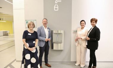Foto von vier Personen am neuen Wasserspender in der Zentralbibliothek. Zu sehen sind vlnr: Martina Leschner, Leitung Zentralbibliothek, Stephan Schwering, Direktor der Stadtbüchereien Düsseldorf, Miriam Koch, Dezernentin für Kultur, Migration und Gesundheit und Tatiana Helfrich von der Stiftung Nachhaltigkeit der Stadtsparkasse