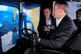 Fahrschule für den Straßenbau: OB Thomas Geisel testet mit HWK-Präsident Andreas Ehlert einen Baggersimulator, mit dem die Bedienung des Gerätes erlernt werden kann; Foto: Gstettenbauer