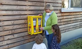 Babette de Fries, Leiterin des Familienzentrums Angermund, mit (v.l.) Emilius und Leona am neuen Bienenfutterautomaten