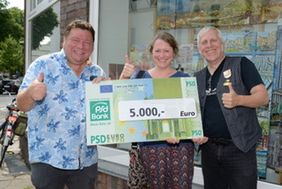 Freuen sich über den Erlös der Schlagermove-on-tour-Party bei der 2. Etappe der Tour de France (v.l.): DJ Günter Sichelschmidt, Arche-Standortleiterin Maike Deckert und Fotokünstler Holger Stoldt. (C) Landeshauptstadt Düsseldorf / Holger Stoldt