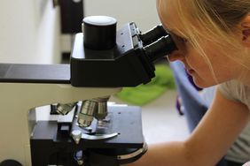 Eine Frau blickt durch ein Mikroskop