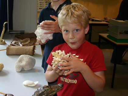 Ein Junge ist erstaunt über die Beschaffenheit der Steinkoralle in seiner Hand