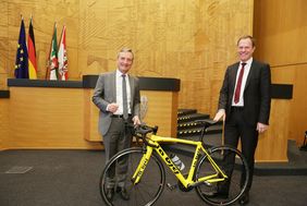 Oberbürgermeister Dr. Stephan Keller übergab seinem Amtsvorgänger Thomas Geisel bei der Verabschiedung im Plenarsaal ein Rennrad.