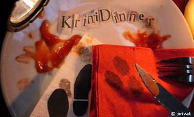 Stilleben mit einem Teller, zwei Messern, Ketchup, das aussieht wie Blut und der Schriftzug "Krimidinner" auf dem Teller.